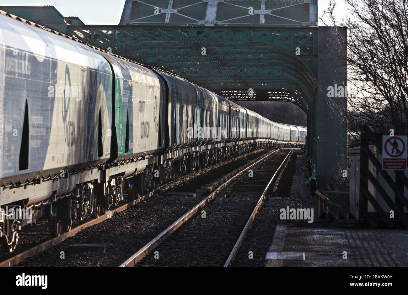 Lungo treno di carri ferroviari Drax Biomass che attraversano il ponte di King George V ad Althorpe, Lincolnshire Foto Stock