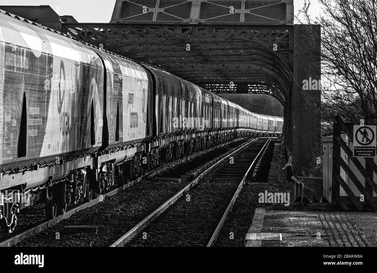 Lungo treno di carri ferroviari Drax Biomass che attraversano il ponte di King George V ad Althorpe, Lincolnshire Foto Stock