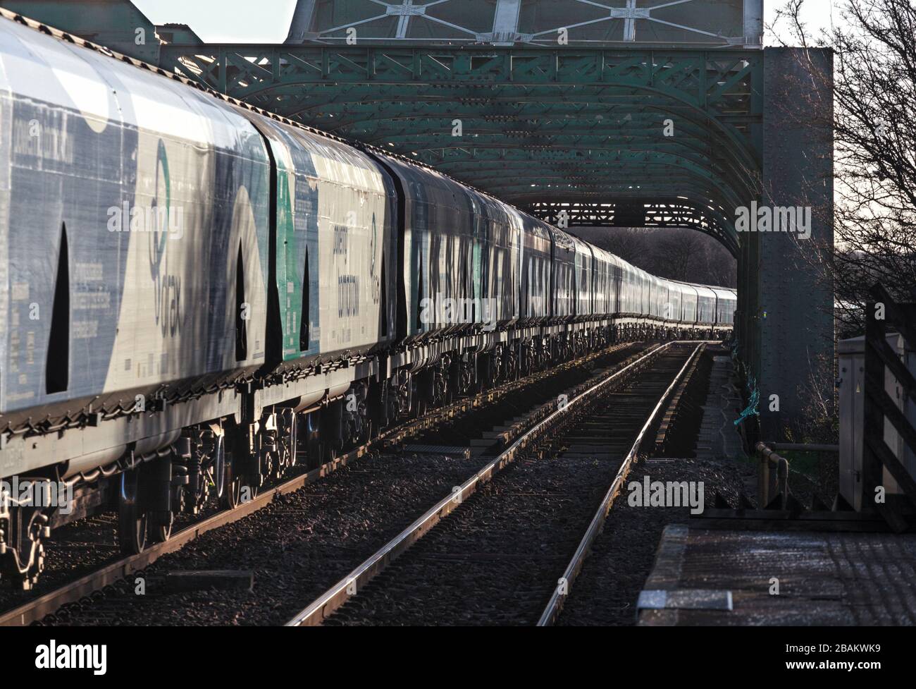 Lungo treno di carri ferroviari Drax Biomass che attraversano il ponte di King George V ad Althorpe, Lincolnshire Foto Stock