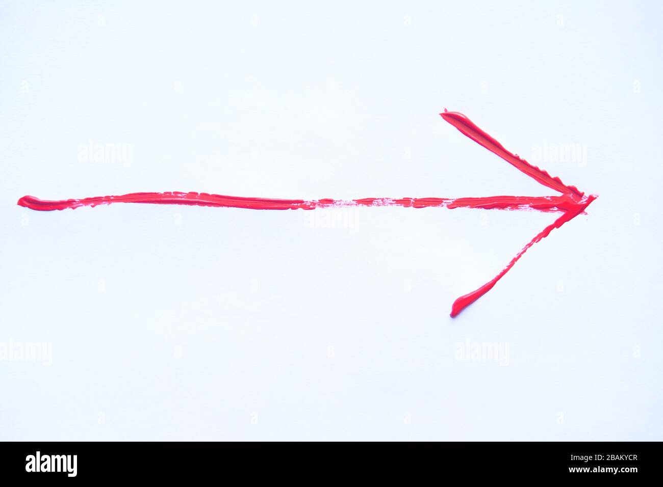 Freccia dipinta a mano rossa con tratti di pennello isolati sullo sfondo bianco. Foto Stock