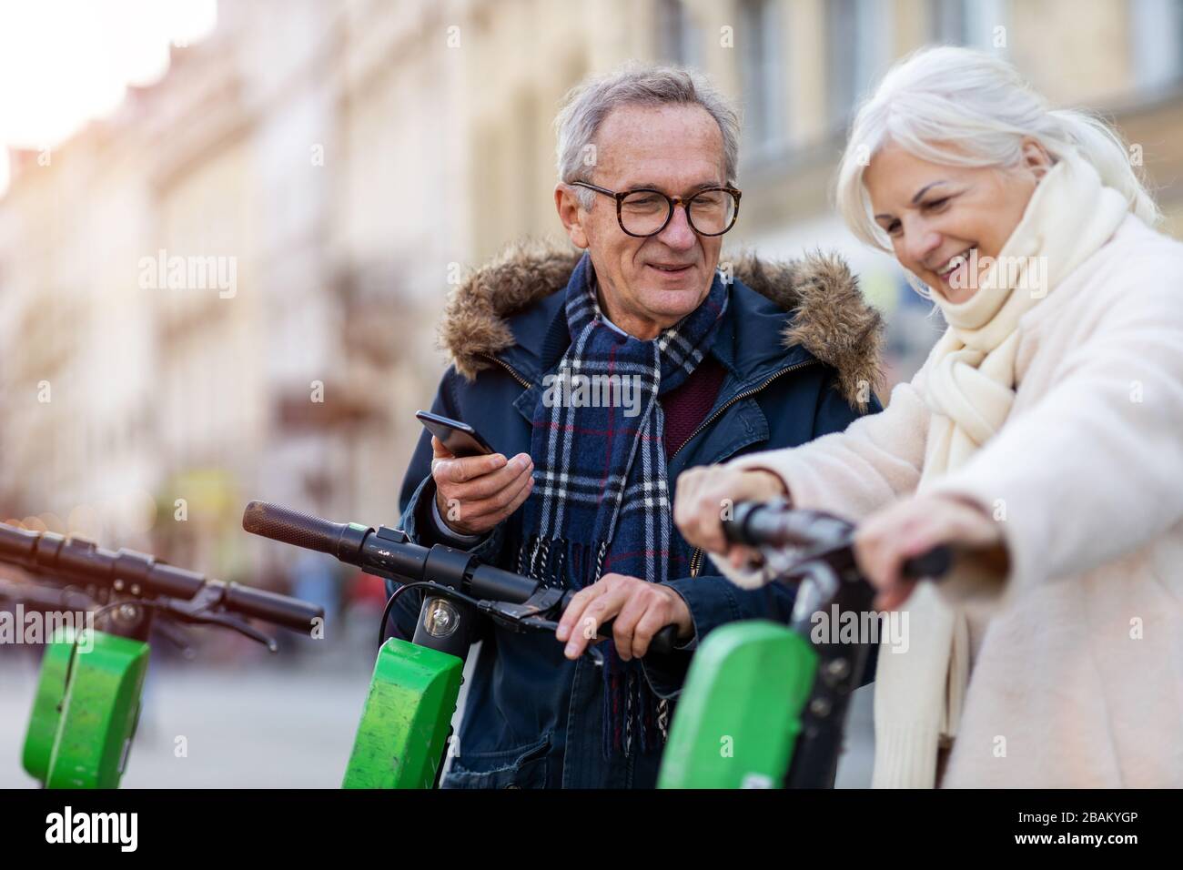 Coppia senior con scooter elettrico e smartphone in città Foto Stock