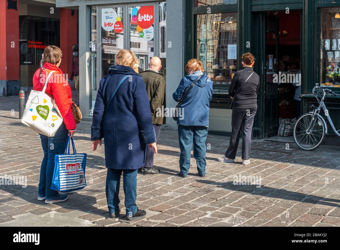 I clienti che attendono fuori in fila davanti al negozio di alimentari a causa della pandemia del 2020 COVID-19 / coronavirus / corona virus nella città fiamminga di Gand, Belgio Foto Stock