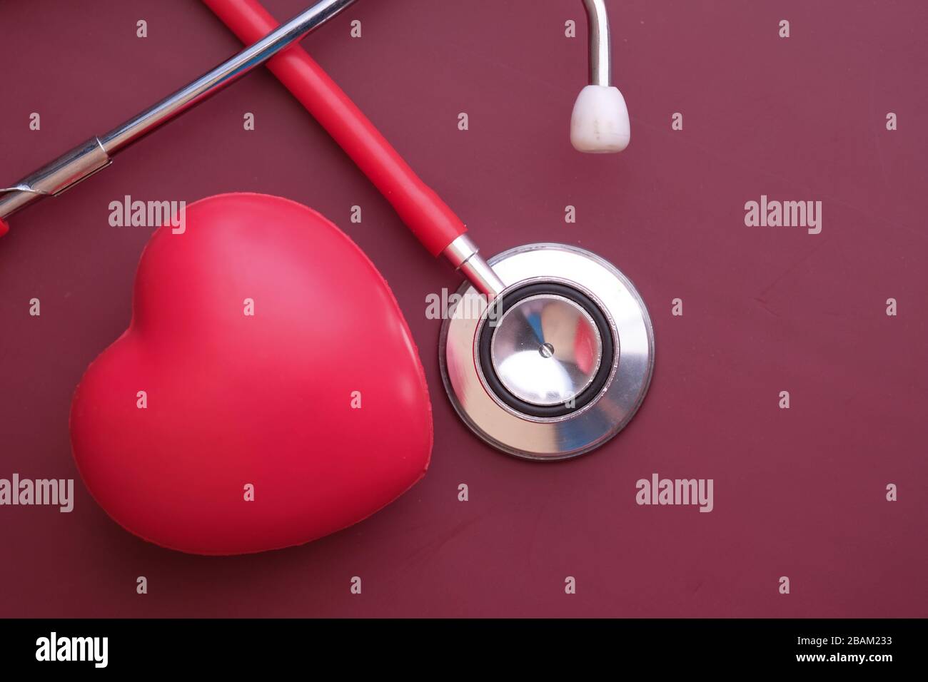 Stetoscopio e cuore su sfondo rosso, vista dall'alto Foto Stock