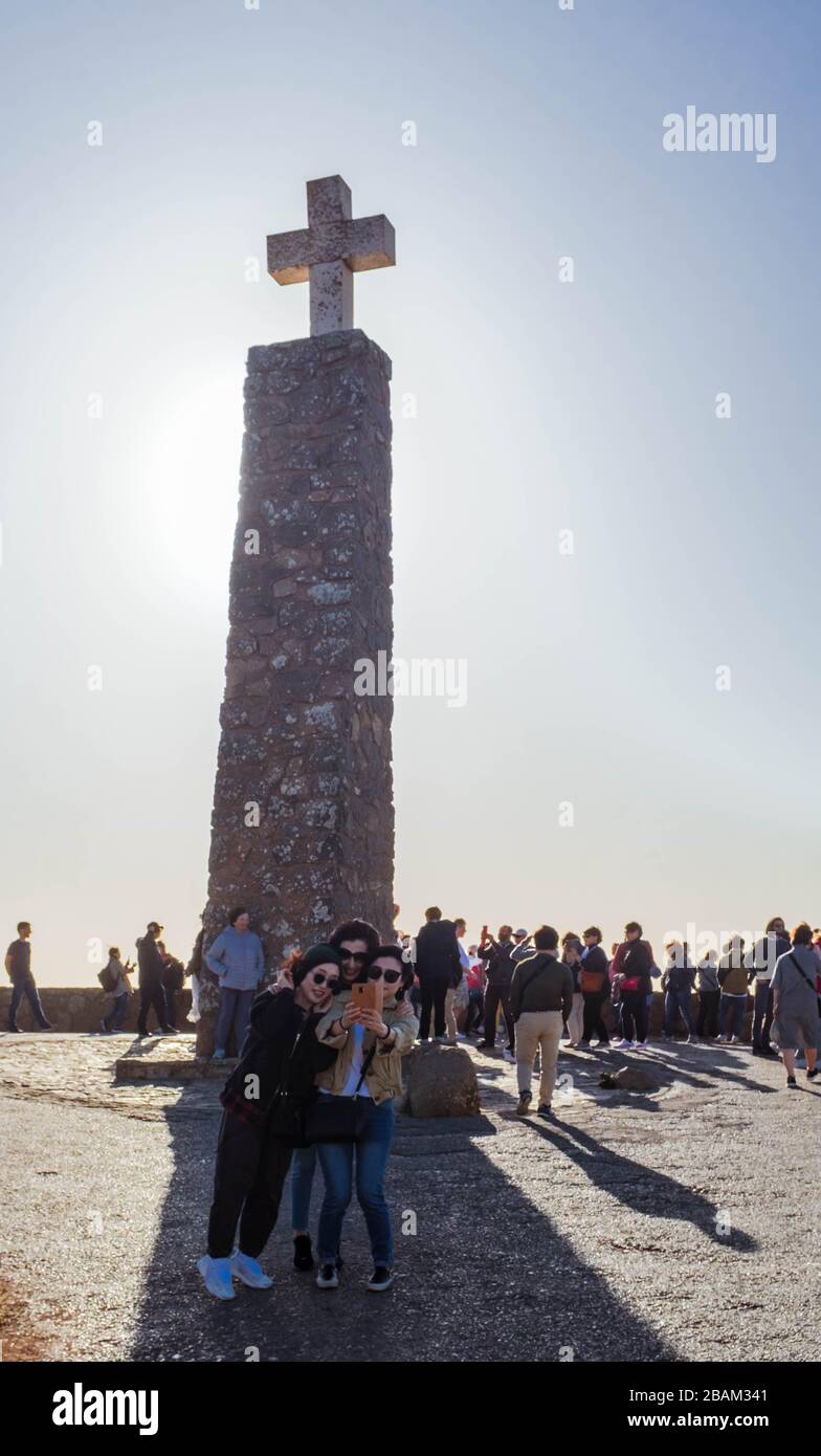 Tre ragazze che prendono un selfie di fronte a un monumento che annuncia Cabo da Roca come il punto più occidentale dell'Europa continentale. Foto Stock