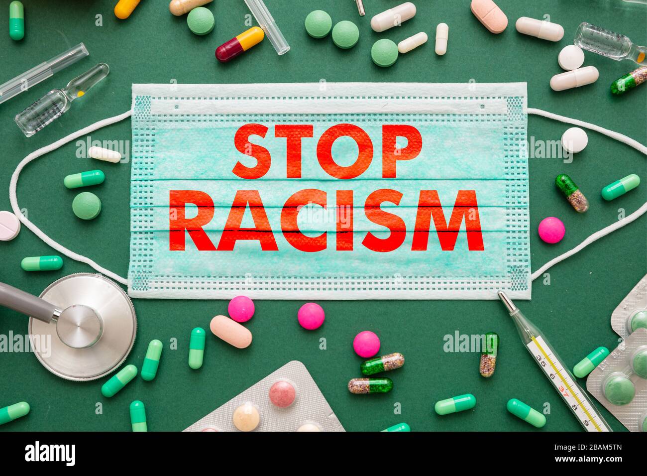 Fermare il razzismo, il concetto di infezione da malattie. Stop razzismo testo su una maschera medica, salute medicina sfondo verde. No al razzismo, messaggio di esclusione sociale f Foto Stock