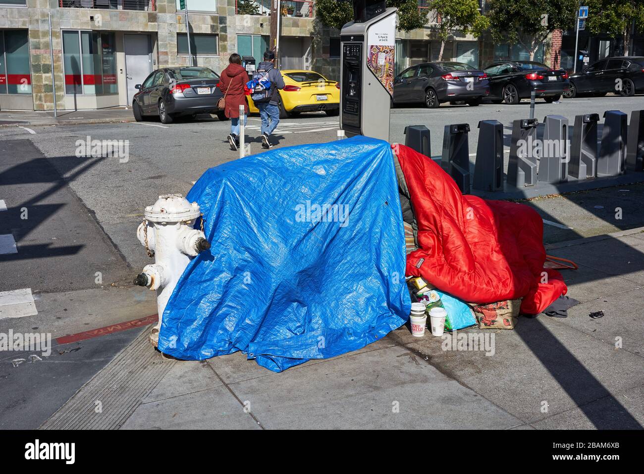 Senzatetto accanto ad un idrante antincendio all'angolo della strada nel quartiere di Soma a San Francisco, California, visto sabato 8 febbraio 2020. Foto Stock