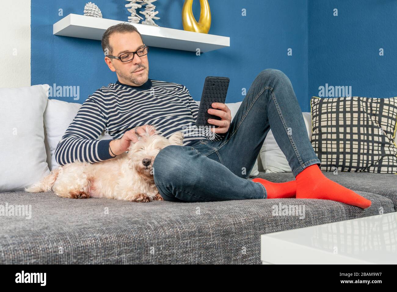 un uomo si rilassa sul divano con il suo cane Foto Stock