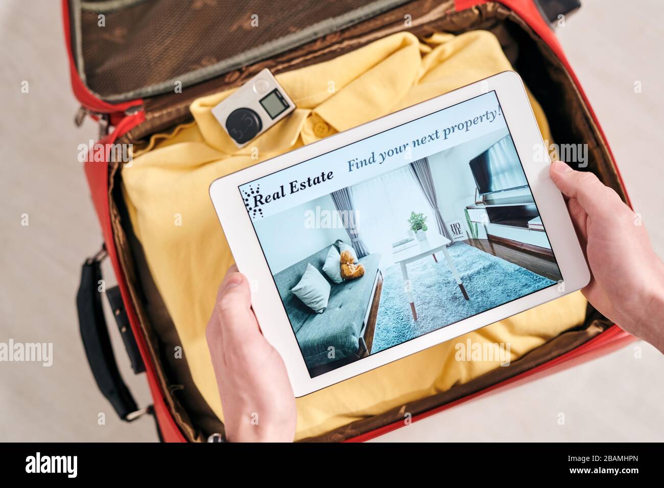 Vista dall'alto di un viaggiatore irriconoscibile che guarda la foto di un appartamento su un tablet mentre scegli l'appartamento in affitto in vacanza Foto Stock