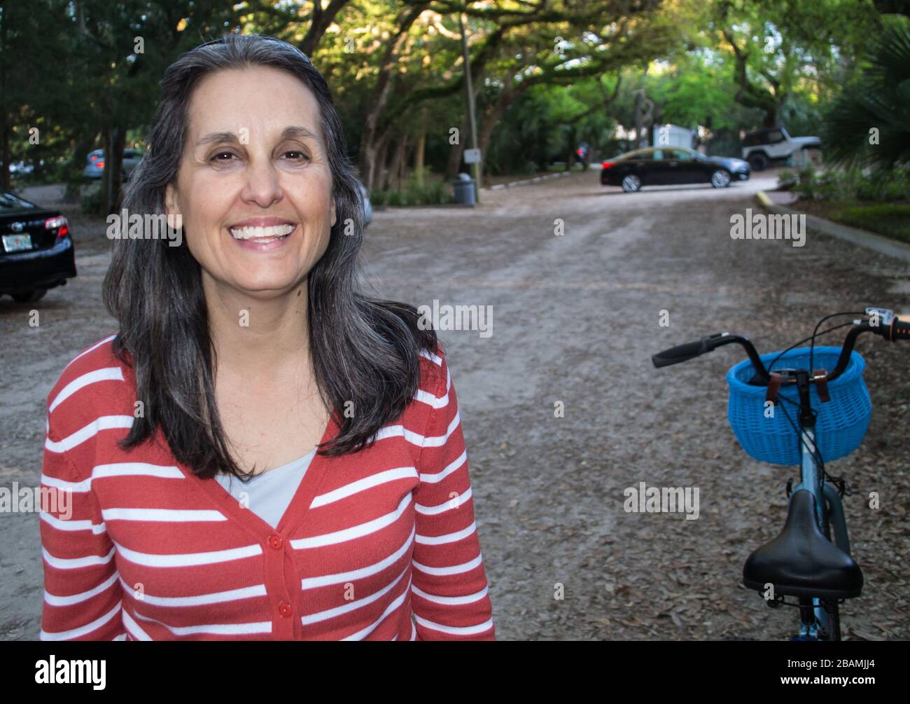 La donna sorridente si riposa dal suo giro in bicicletta Foto Stock