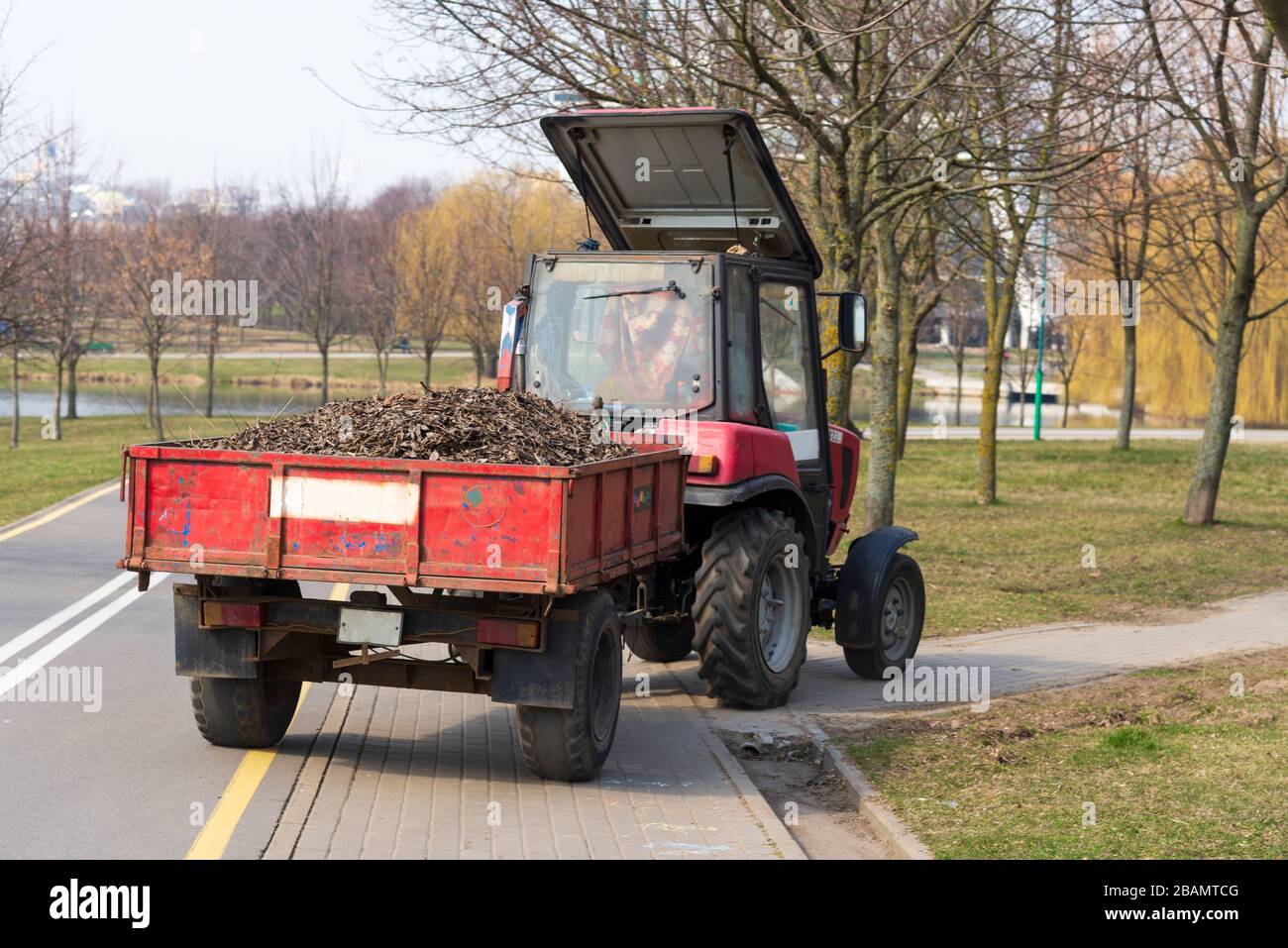 Il trattore parte dalle strade della città di pulizia, pulendo le strade della città di primavera Foto Stock