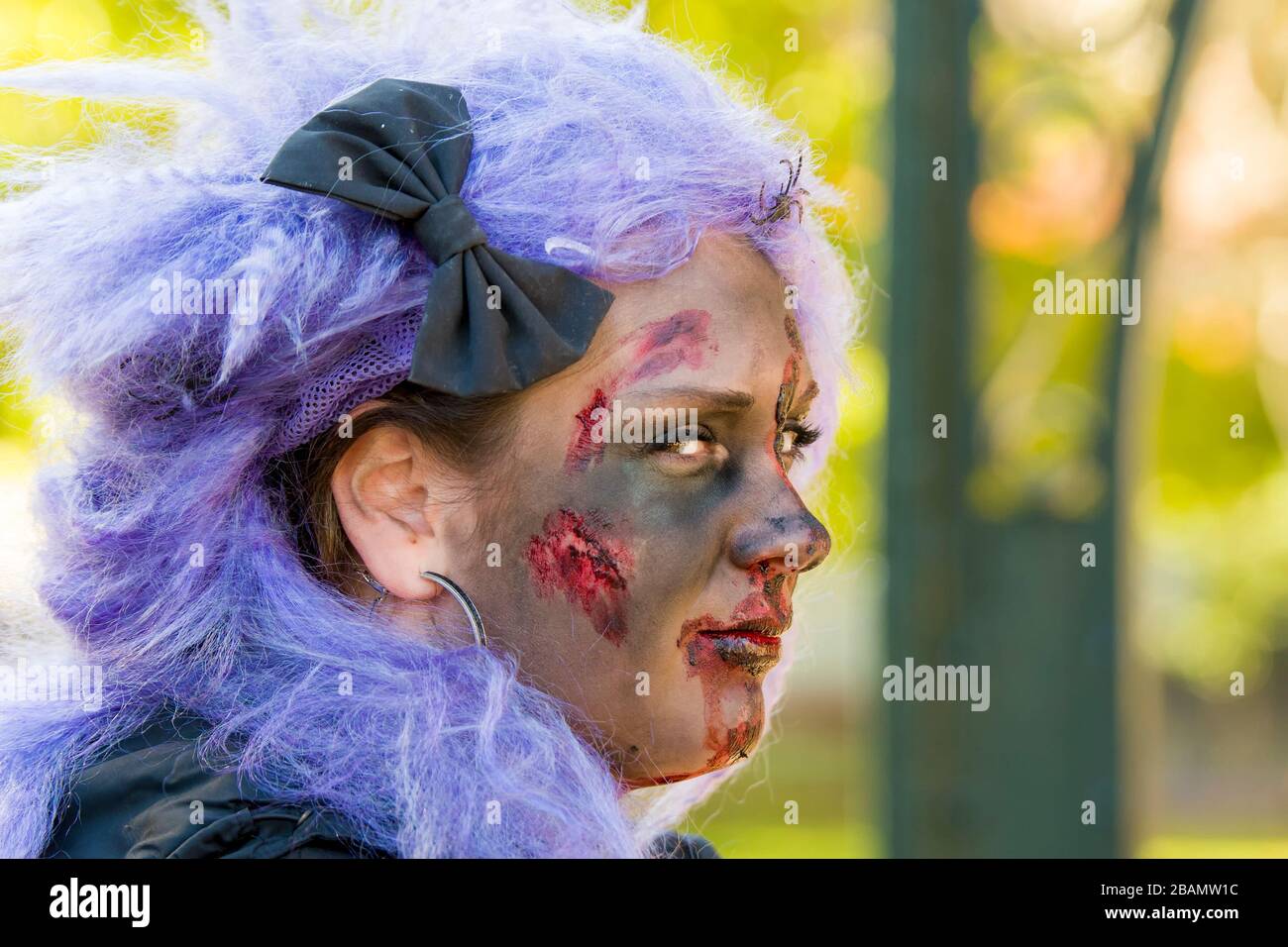 Saint John, New Brunswick, Canada - 21 ottobre 2017: Passeggiata zombie. Una zombie femminile con capelli viola ha tagli e sangue sul suo volto sporco. Foto Stock