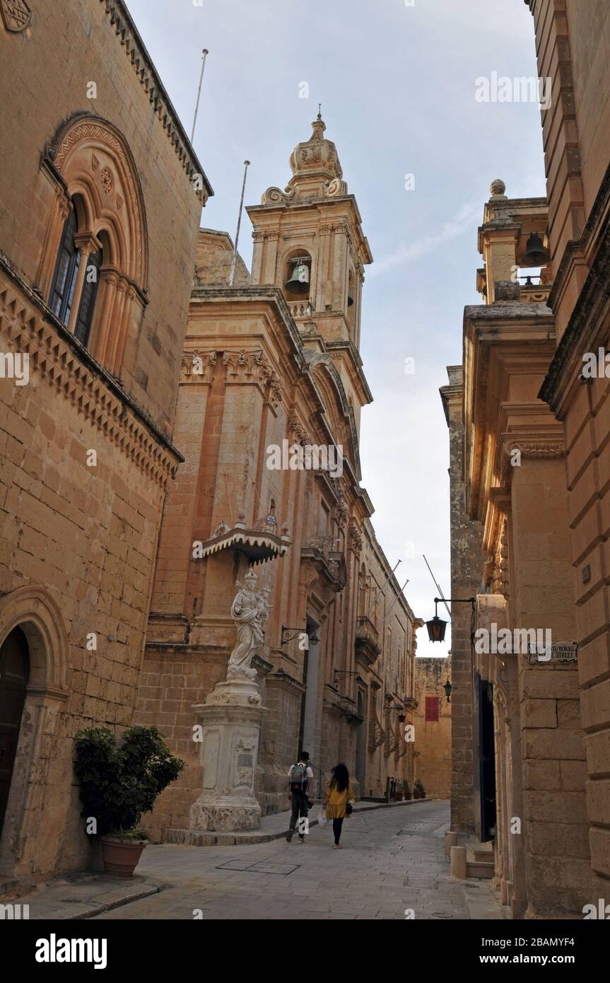 La gente cammina lungo una strada nella storica città murata di Mdina, Malta. Conosciuta come la Città silenziosa, Mdina è una destinazione popolare per i turisti. Foto Stock
