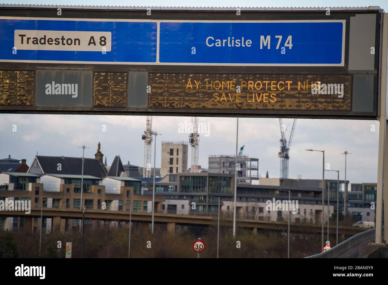 Glasgow, Regno Unito. 28 Marzo 2020. Nella foto: Segnaletica stradale lungo le autostrade M8 e M80 che recita: "STAY HOME PROTECT NHS SAVE LIVES" il Coronavirus Pandemic ha costretto il governo britannico a chiudere tutte le principali città del Regno Unito e a far sì che le persone restino a casa, che ha lasciato le autostrade e tutte le altre strade libere dal solito traffico naso a coda che altrimenti sarebbe lì. Credit: Colin Fisher/Alamy Live News Foto Stock