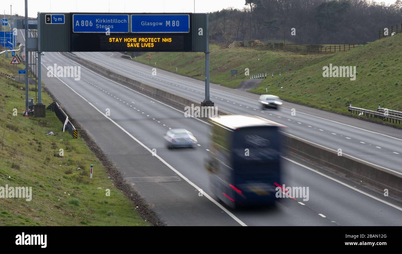 Glasgow, Regno Unito. 28 Marzo 2020. Nella foto: Segnaletica stradale lungo le autostrade M8 e M80 che recita: "STAY HOME PROTECT NHS SAVE LIVES" il Coronavirus Pandemic ha costretto il governo britannico a chiudere tutte le principali città del Regno Unito e a far sì che le persone restino a casa, che ha lasciato le autostrade e tutte le altre strade libere dal solito traffico naso a coda che altrimenti sarebbe lì. Credit: Colin Fisher/Alamy Live News Foto Stock