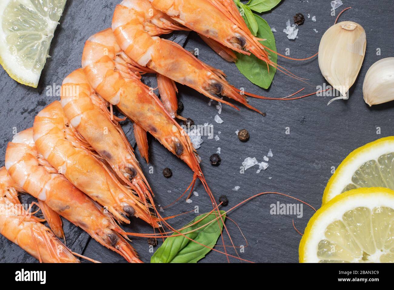 Gamberi rossi bolliti con aglio e limone su sfondo scuro Foto Stock