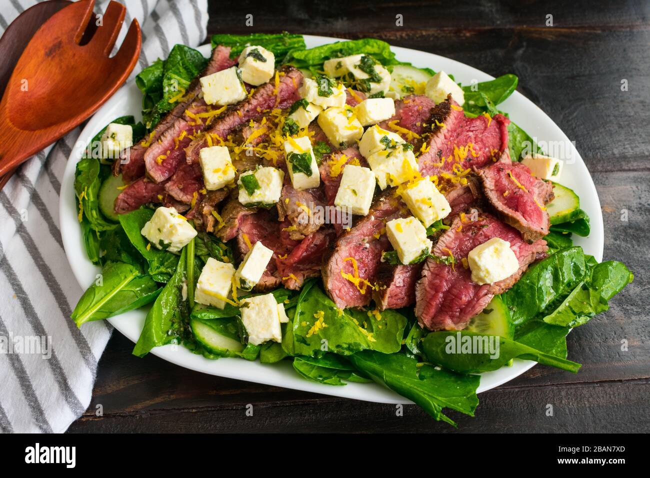 Insalata di bistecca e feta: Spinaci e insalata di erbe fresche con bistecca di fianco rara, formaggio feta marinato e scorza di limone Foto Stock