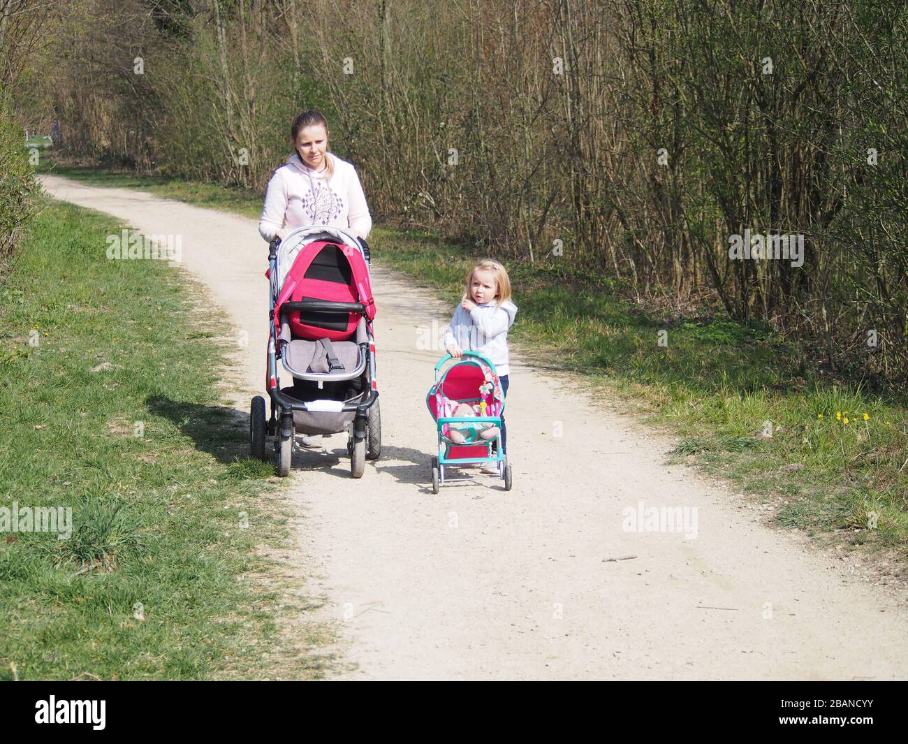 Madre e figlia camminano a fianco con il loro Baby Buggy in estate Foto Stock