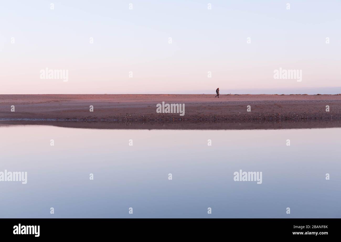 Donna che cammina sulla spiaggia di Aberdeen si riflette nel fiume Don, Scozia Foto Stock