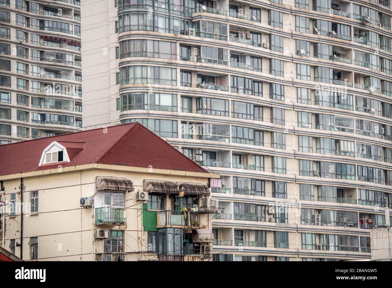 Un grande edificio di appartamenti che domina un piccolo edificio rustico, Shanghai, Cina Foto Stock
