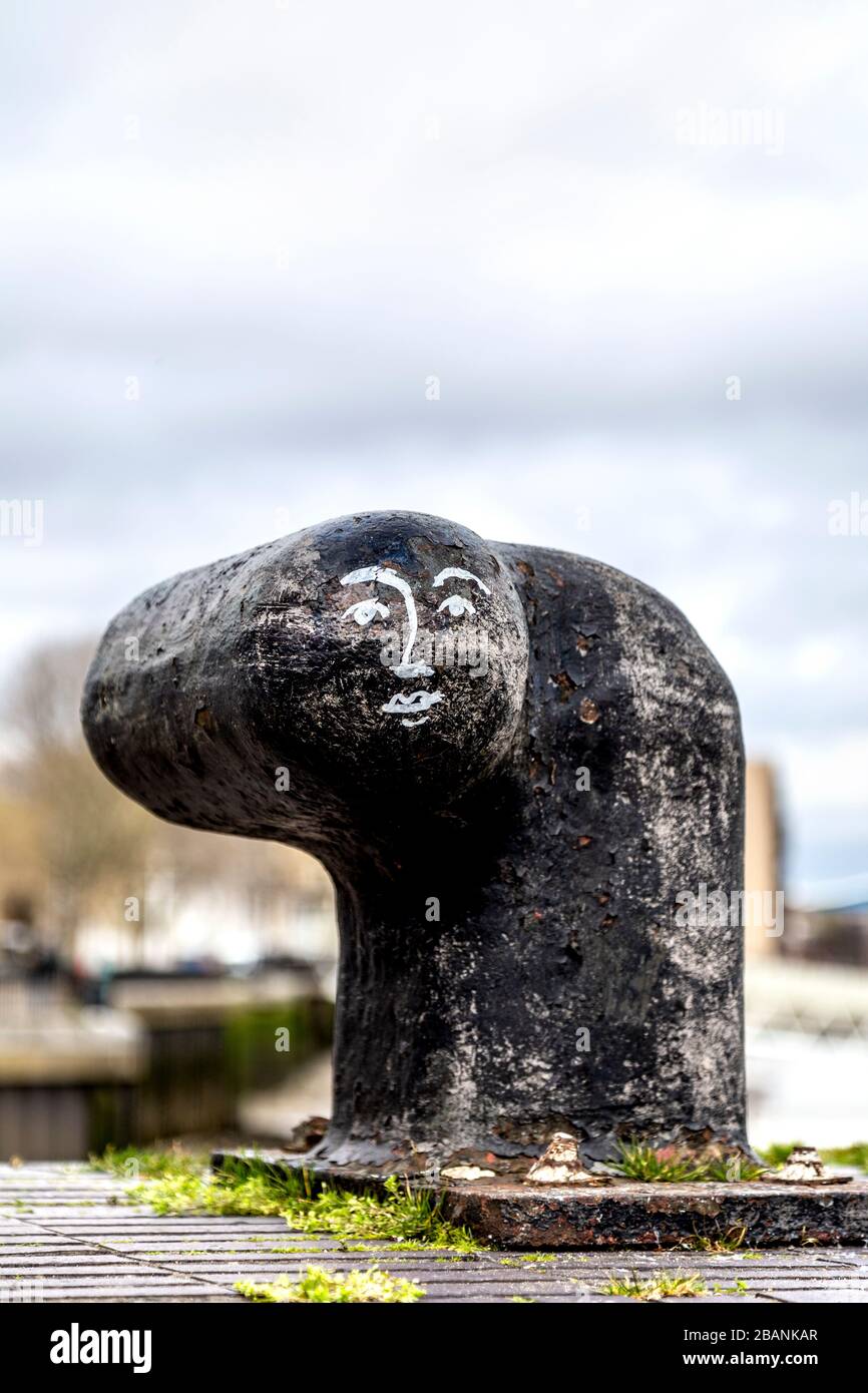 Una faccia dipinta su un paletto ormeggiabile lungo il Thames Path, Londra, Regno Unito Foto Stock