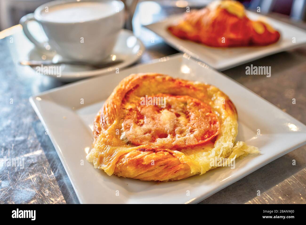 Prima colazione torta di pomodoro pasta sfoglia condita con formaggio e una tazza di caffè latte. Foto Stock