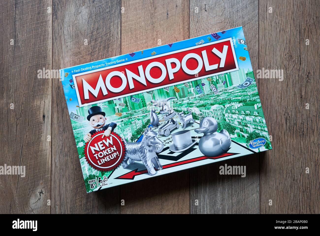 Scatola del gioco del bordo di monopolio isolata su uno sfondo di legno. Il classico gioco di tavola di trading di proprietà ad alta velocità è attualmente pubblicato da Hasbro. Foto Stock