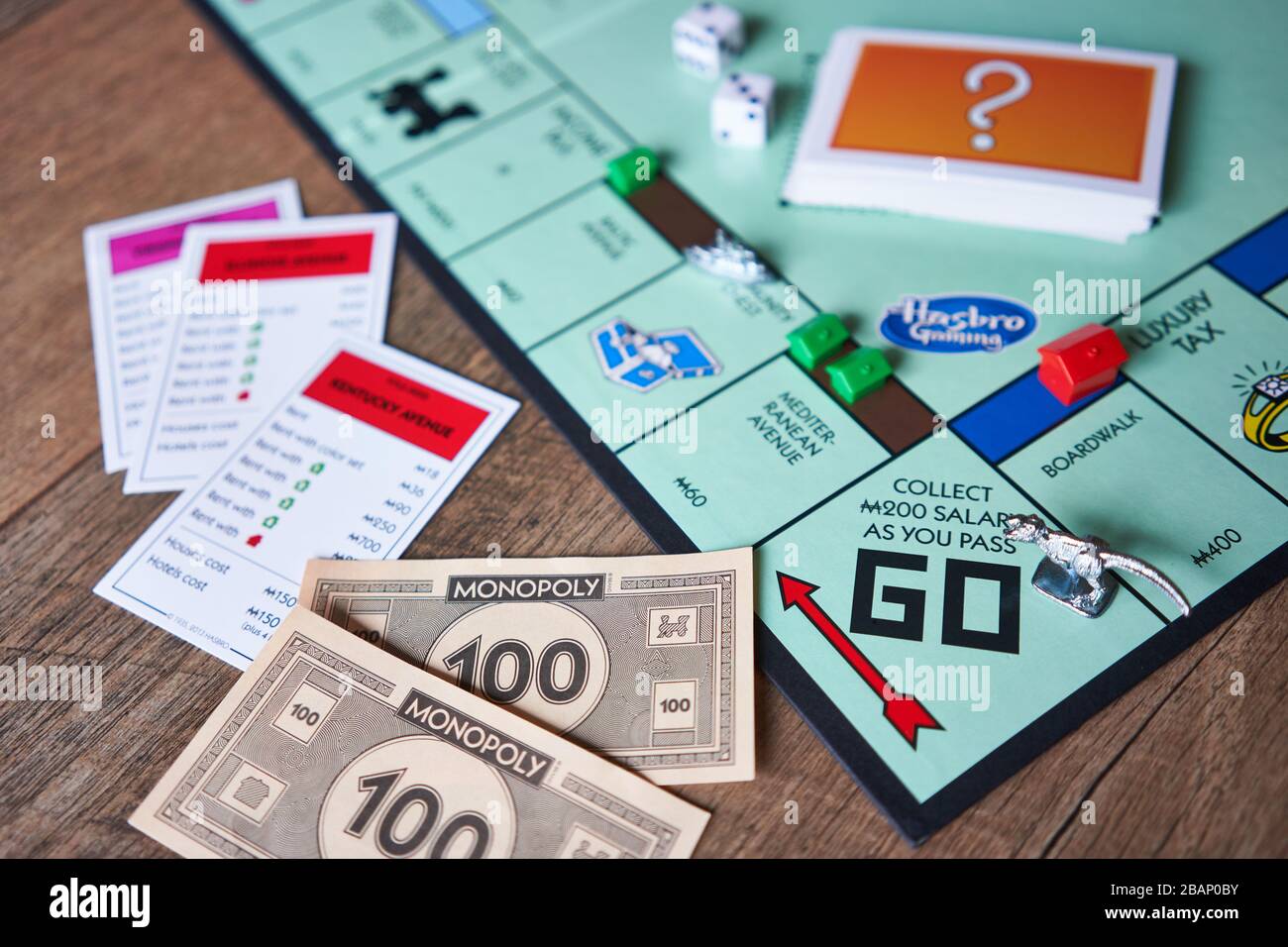 Primo piano del gioco di bordo di monopolio isolato su uno sfondo di legno. Il classico gioco di tavola di trading di proprietà ad alta velocità è attualmente pubblicato da Hasbro. Foto Stock