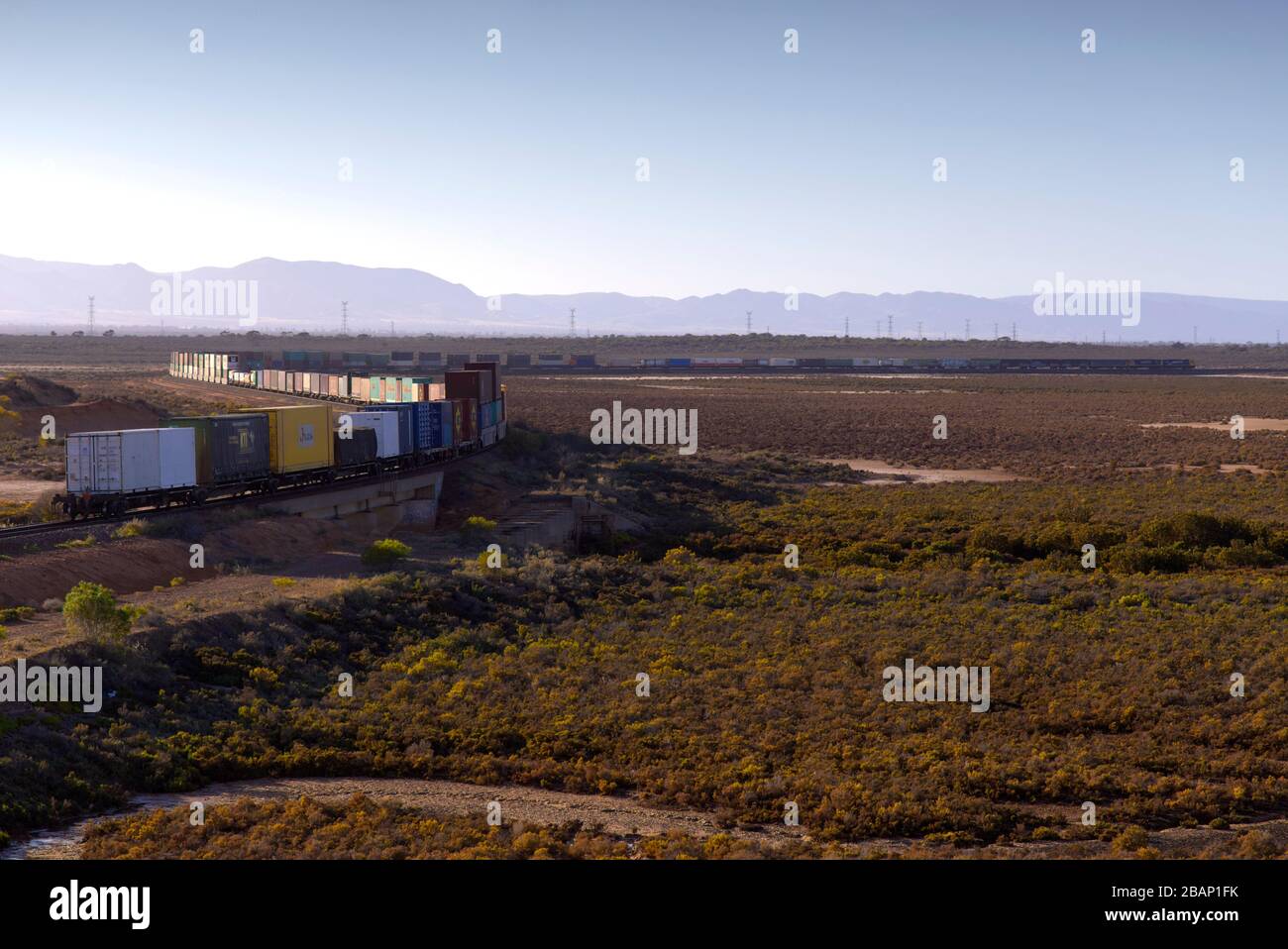 Trasporto di treni a doppia pila - trasporto di container attraverso il paesaggio pianeggiante vicino a Port Auguata South Australia Foto Stock