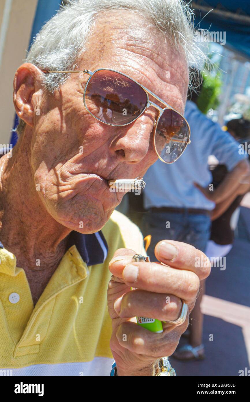 Miami Beach Florida,uomo ispanico uomini maschio adulti, anziani cittadini anziani, fumatore, fumo, illuminazione sigaretta, salute, accendino, abitudine, polmone può Foto Stock