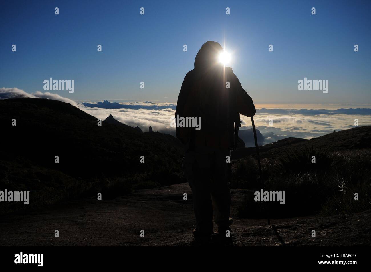 Alpinista che guarda l'alba a Pedra do Açú (2.245 m) nel Parco Nazionale della Serra dos Órgãos, nel punto più alto della città di Petrópolis. Foto Stock