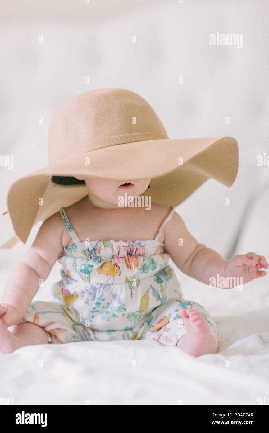 baby girl seduto con cappello da sole che copre gli occhi Foto Stock