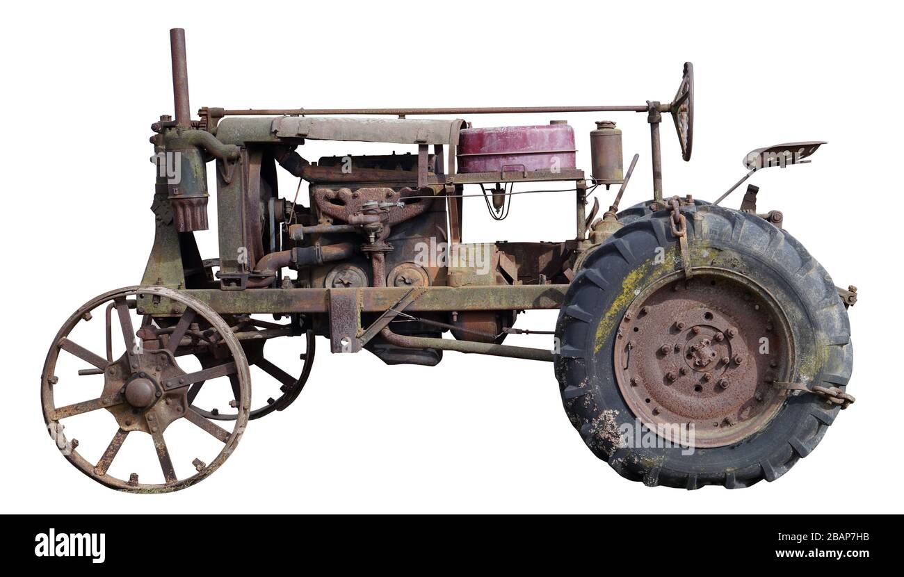 Arrugginito retrò piccolo rurale senza nome trattore. L'apparecchiatura di acciaio l è fatta più di cento anni fa. Produzione di massa. Isolato su bianco Foto Stock