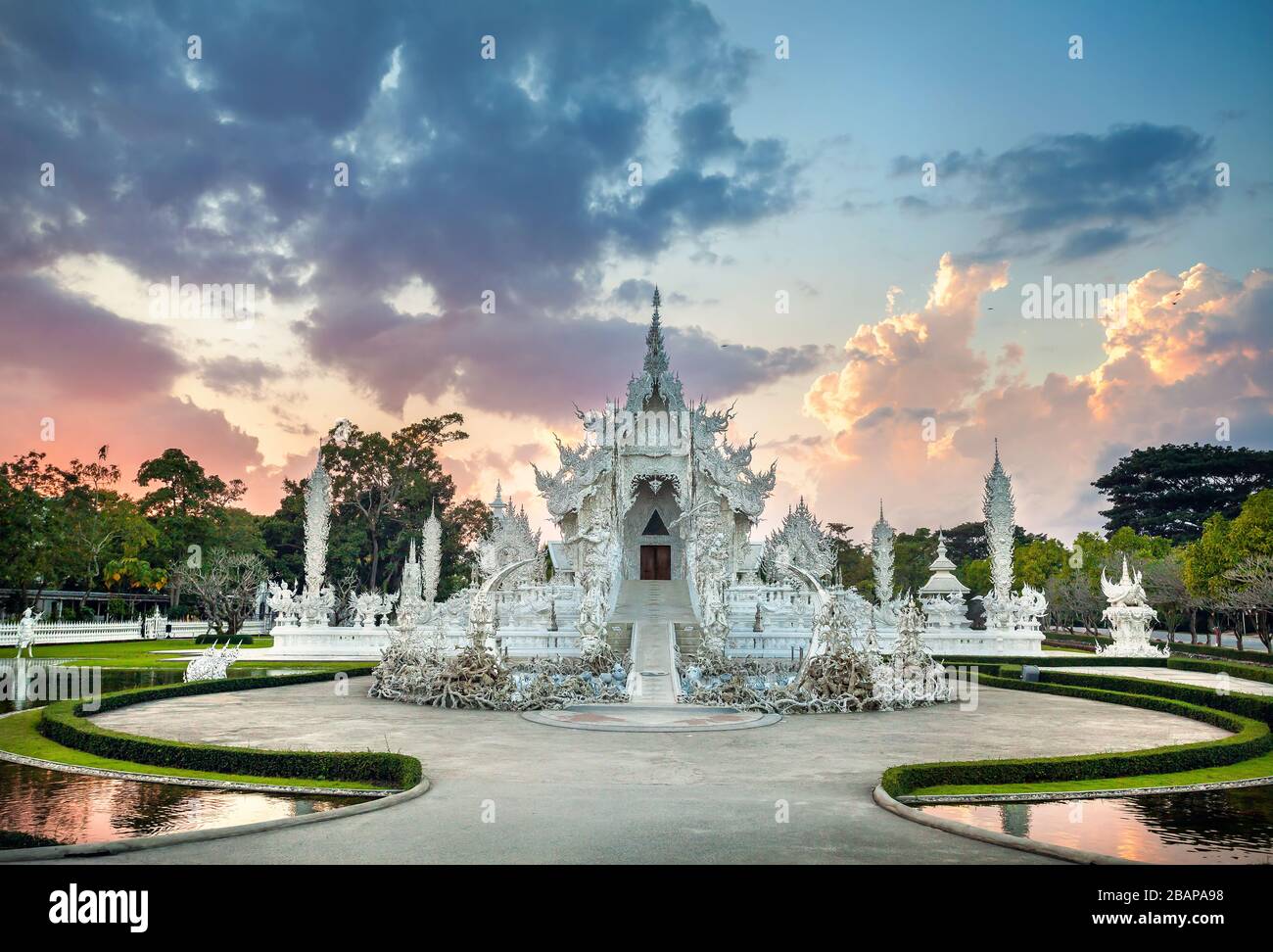 Wat Rong Khun il tempio bianco e uno stagno al tramonto spettacolare sfondo in Chiang Rai, Thailandia Foto Stock