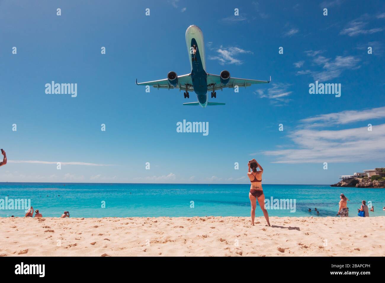 Un Delta Air Lines Boeing 757 vola su una donna scattando una foto su Maho Beach mentre atterra a SXM Foto Stock
