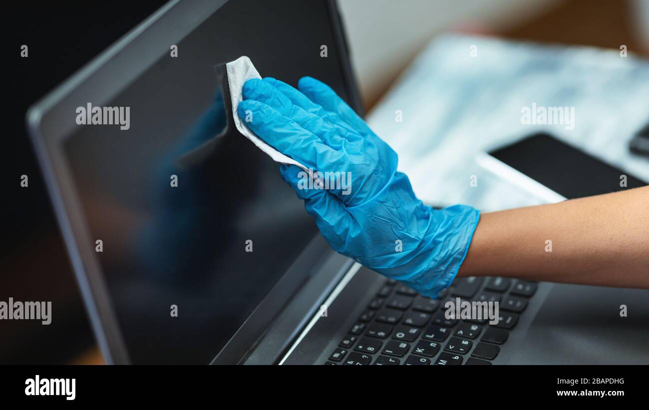 Donna in quarantena indossando guanti per la pulizia del computer portatile Foto Stock
