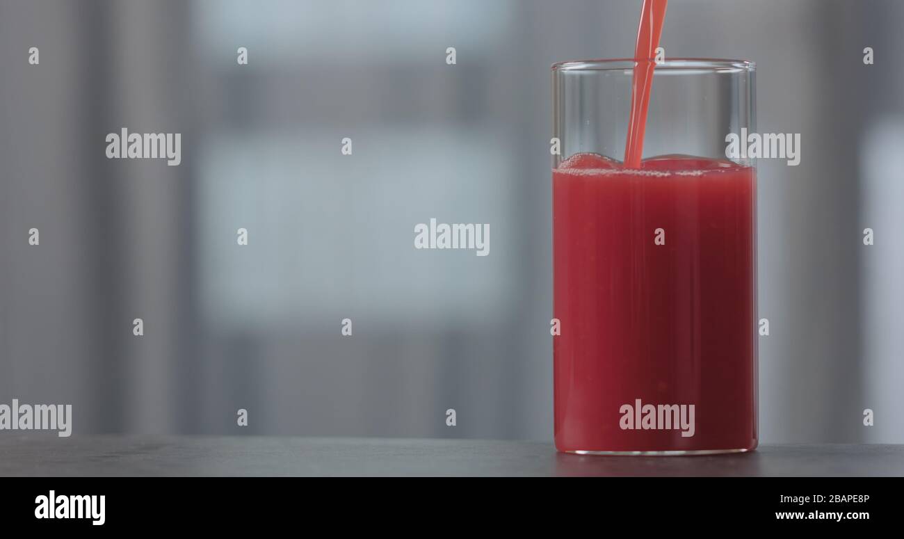 versare il succo d'arancia rosso nel vetro su un piano di cemento con spazio per la copia, foto ampia Foto Stock