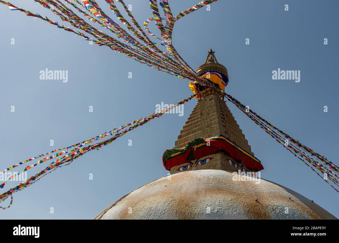 Boudha Stupa, nella città di Kathmandu in Nepal contro il cielo blu, con bandiere colorate religiose ondeggiante. Foto Stock
