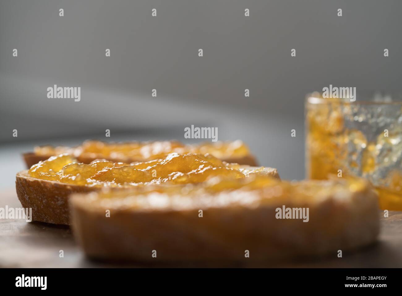 Fette di ciabatta con marmellata d'arancia su tavola d'oliva Foto Stock