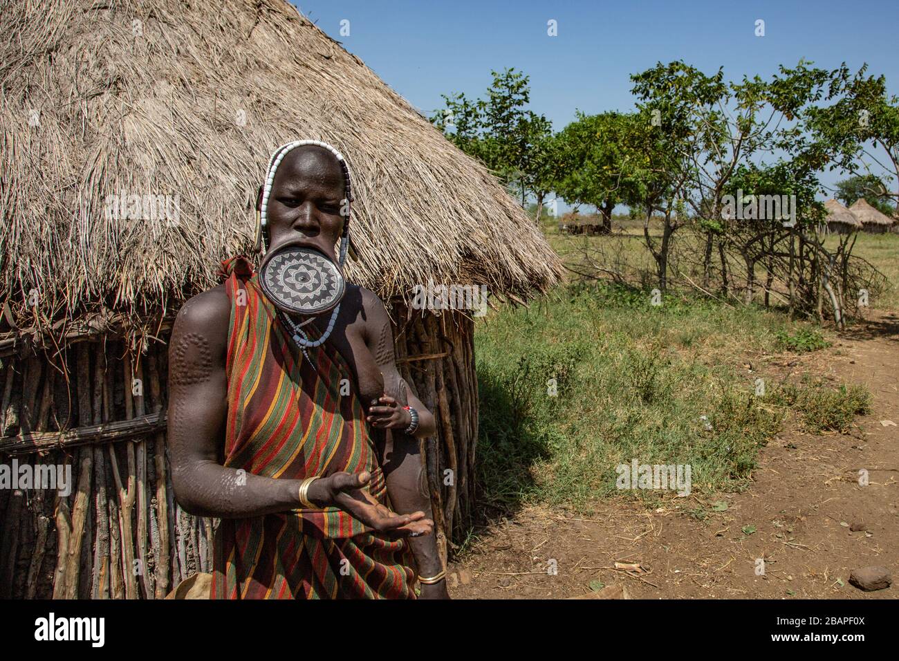 Donna della tribù Mursi con disco di argilla labbro come corpo che tiene un bambino, Mago National Park, Etiopia meridionale, Africa Foto Stock