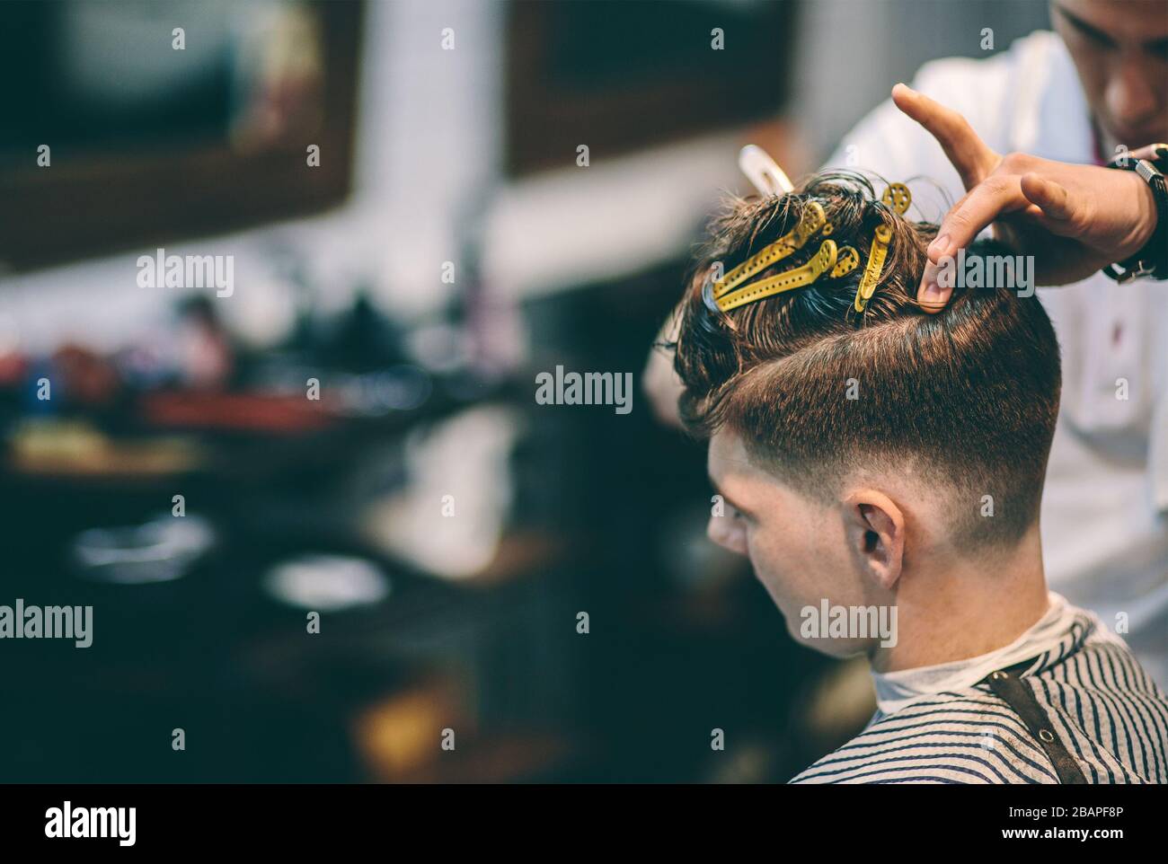 Il parrucchiere rende l'acconciatura un uomo con una clip sulla testa in un parrucchiere Foto Stock