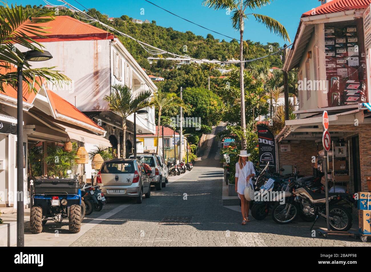 Una donna in bianco abbigliamento estivo cammina lungo una strada tranquilla a Gustavia, capitale di San Barthélemy Foto Stock