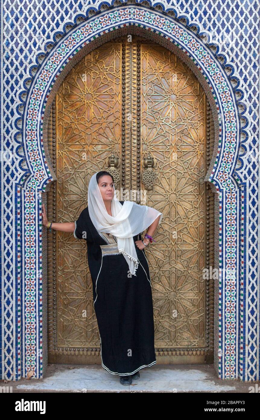 Una giovane donna in un velo che si trova davanti alla porta del Palazzo reale a Fes Foto Stock