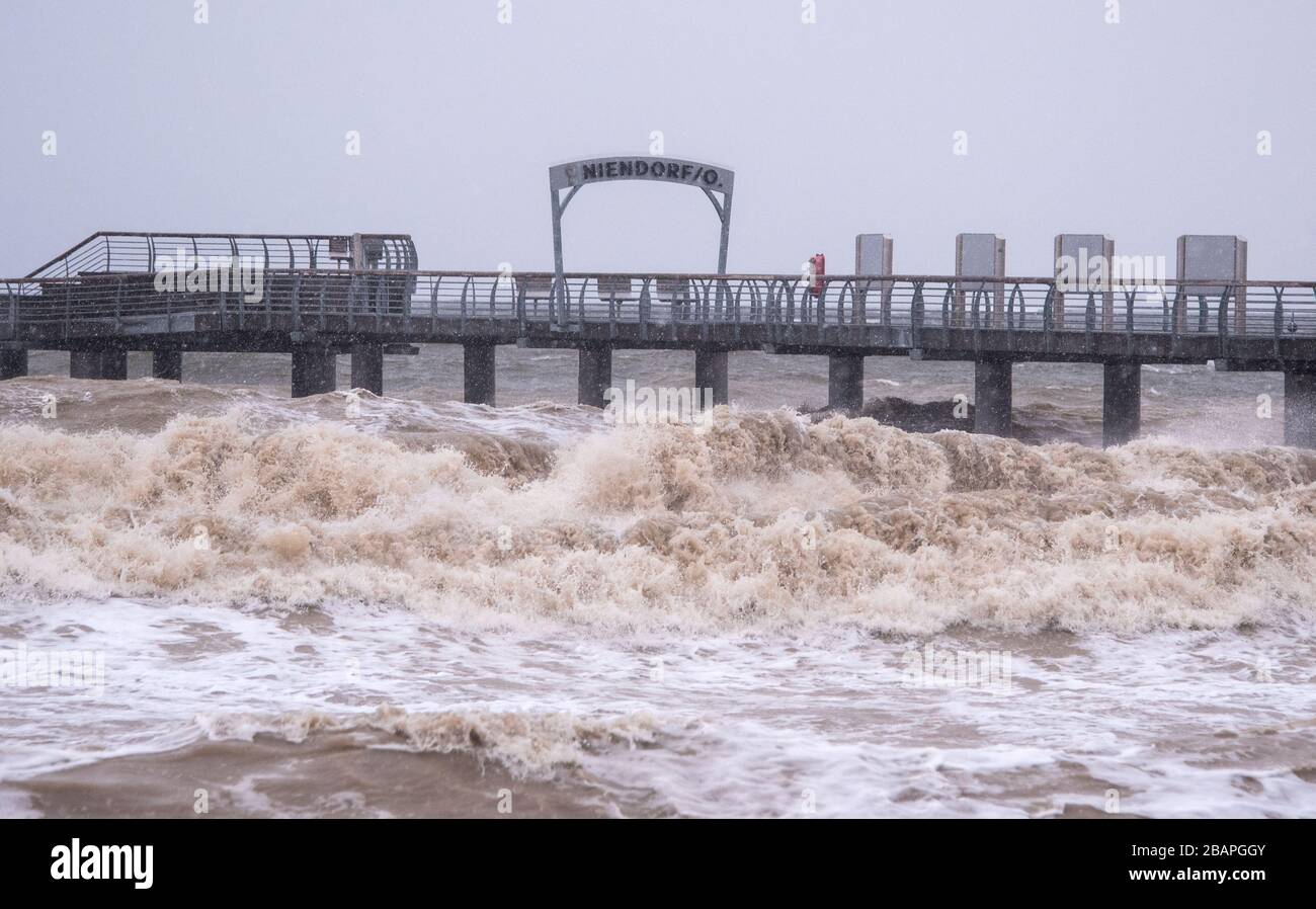 29 marzo 2020, Schleswig-Holstein, Niendorf/Ostsee: Durante una tempesta le onde si lavano intorno al molo sulla spiaggia del Mar Baltico. Foto: Daniel Bockwoldt/dpa Foto Stock