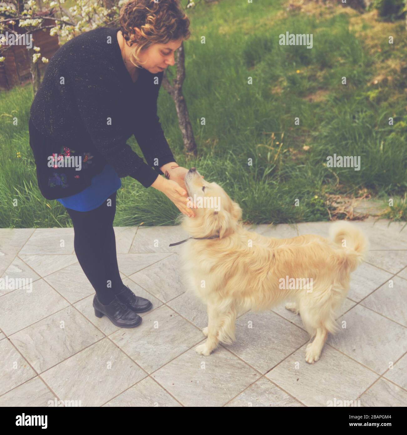 Una donna caucasica gioca con il suo animale domestico nel giardino Foto Stock