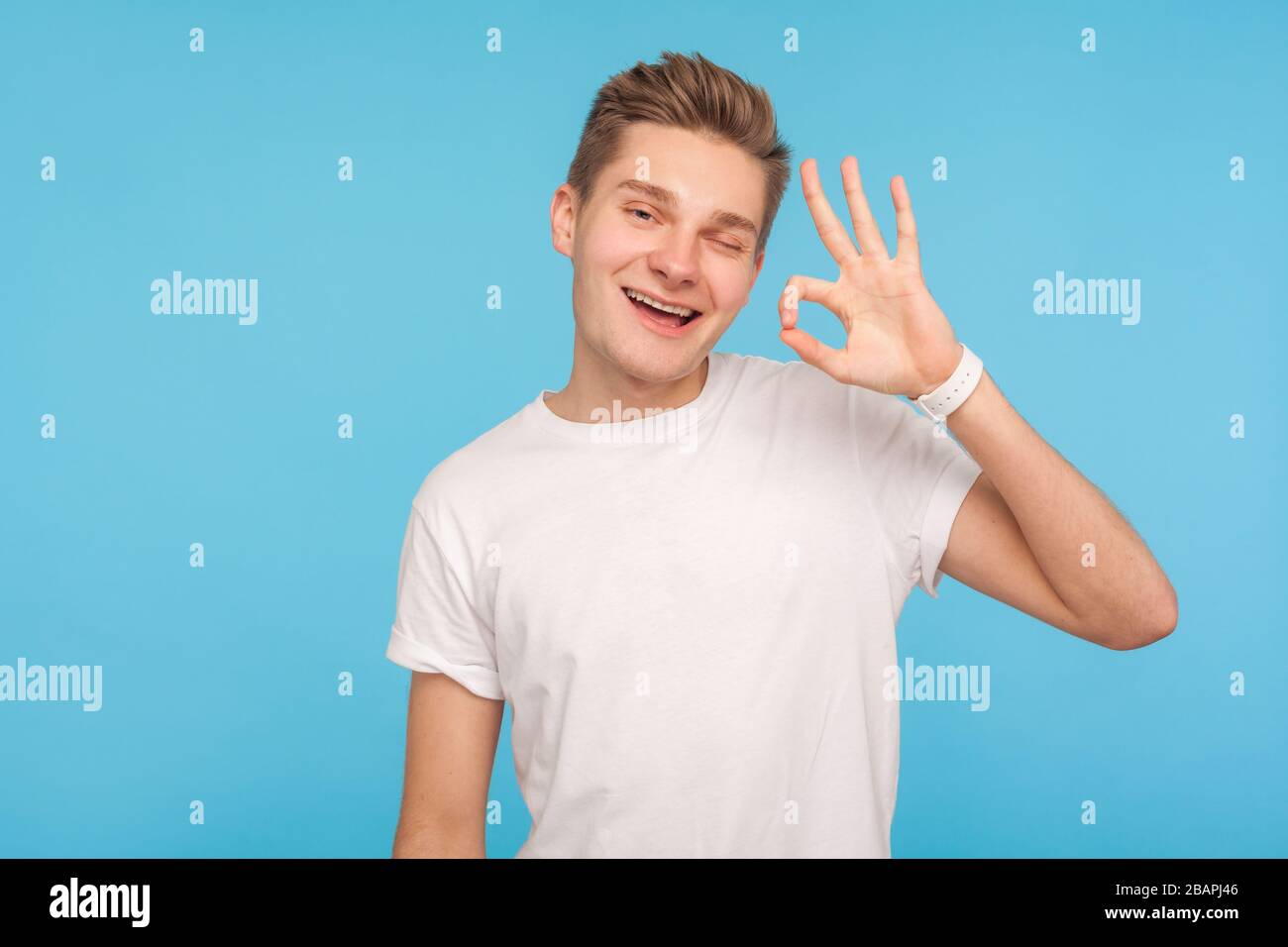 Sto bene! Ritratto di uomo positivo in maglietta bianca casual che strizza e mostra OK gesto, indicando approvazione, accordo, soddisfatto con suggerimento. In Foto Stock