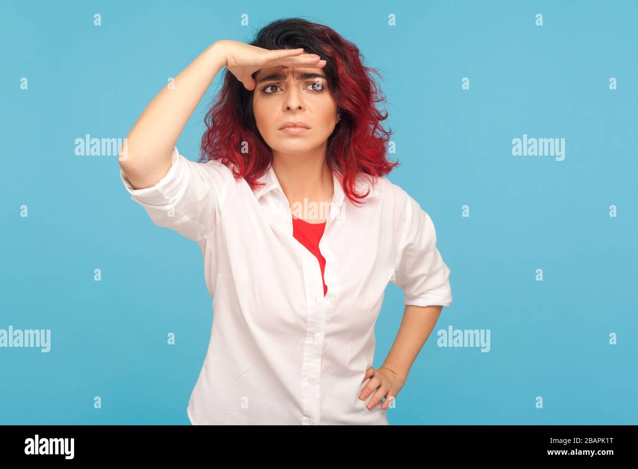 Futuro lontano. Ritratto di donna hippster con capelli rossi tenere mano sugli occhi e guardare lontano, aspettandosi qualcosa con expresssi preoccupato Foto Stock