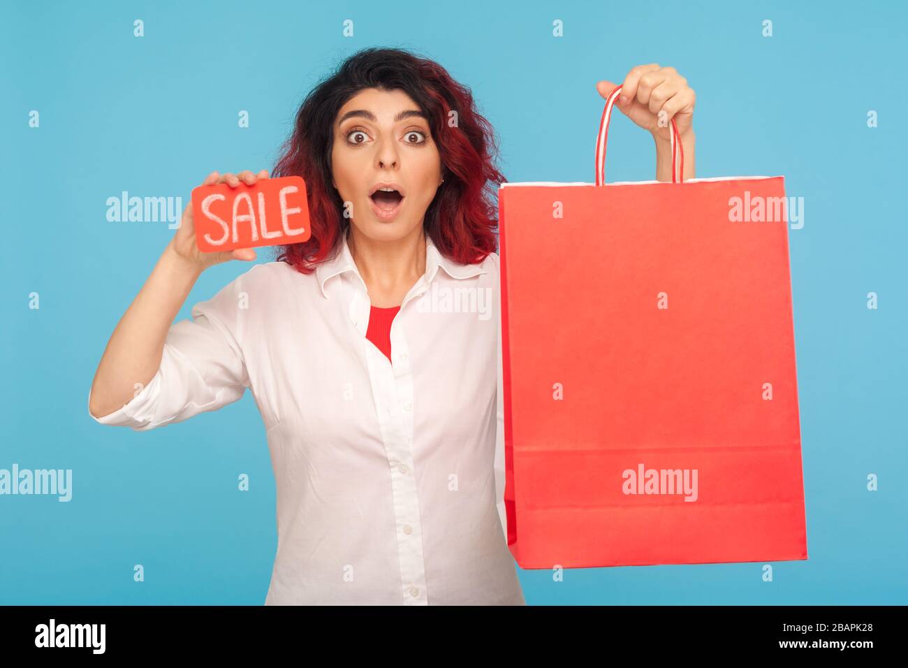 Incredibile sconto nel negozio di moda. Bella donna hippster allegro con  capelli rossi fantasia mostrando vendita parola e borse per lo shopping,  godendo il venerdì nero, lo Foto stock - Alamy