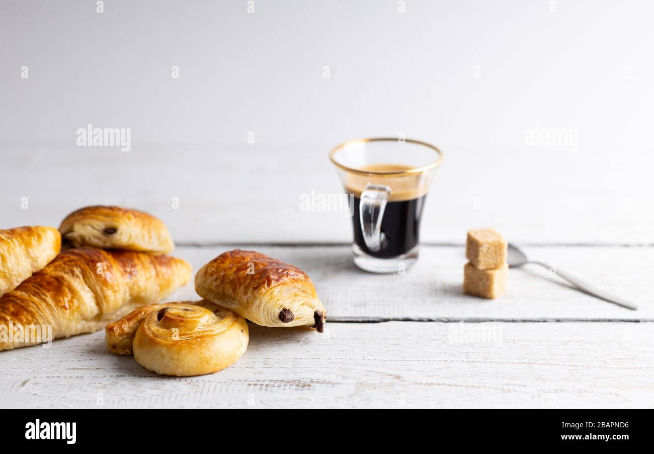 Colazione con croissant, dolci alla cannella e cioccolato, succo d'arancia fresco e caffè sul lato su sfondo bianco. Foto Stock