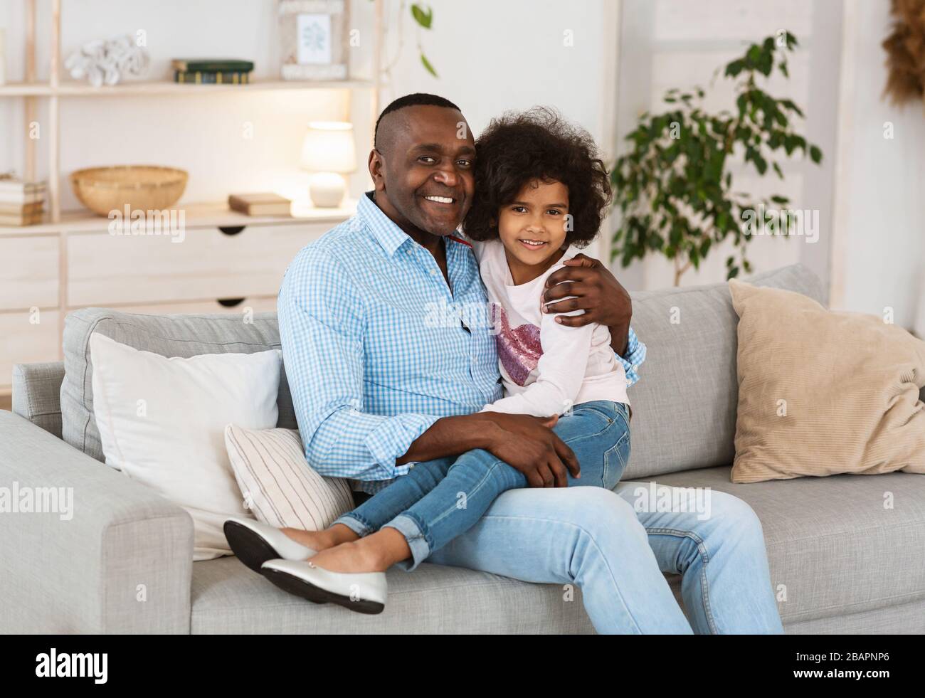 Concetto di soggiorno a casa. Nonno americano africano con sua nipote che trascorre il tempo insieme all'interno Foto Stock