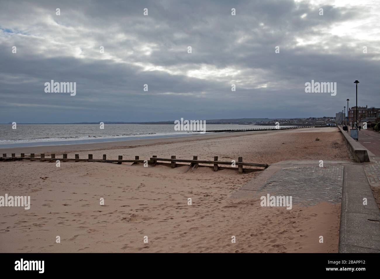 Portobello, Edimburgo, Scozia, Regno Unito. 29 marzo 2020. Moody vuota spiaggia in questa mattina nuvolosa a 3 gradi centigradi con il raggio occasionale di sole che sbirciano attraverso le nuvole. Normalmente, ci sarebbero molti più camminatori del cane e pedoni che sono visibili questa mattina. Foto Stock